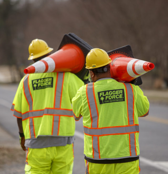 Employees working together carrying cones while setting up a work zone