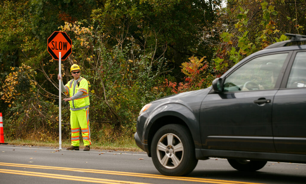 Flagger Force male flagger in work zone telling traffic to slow down and travel through zone